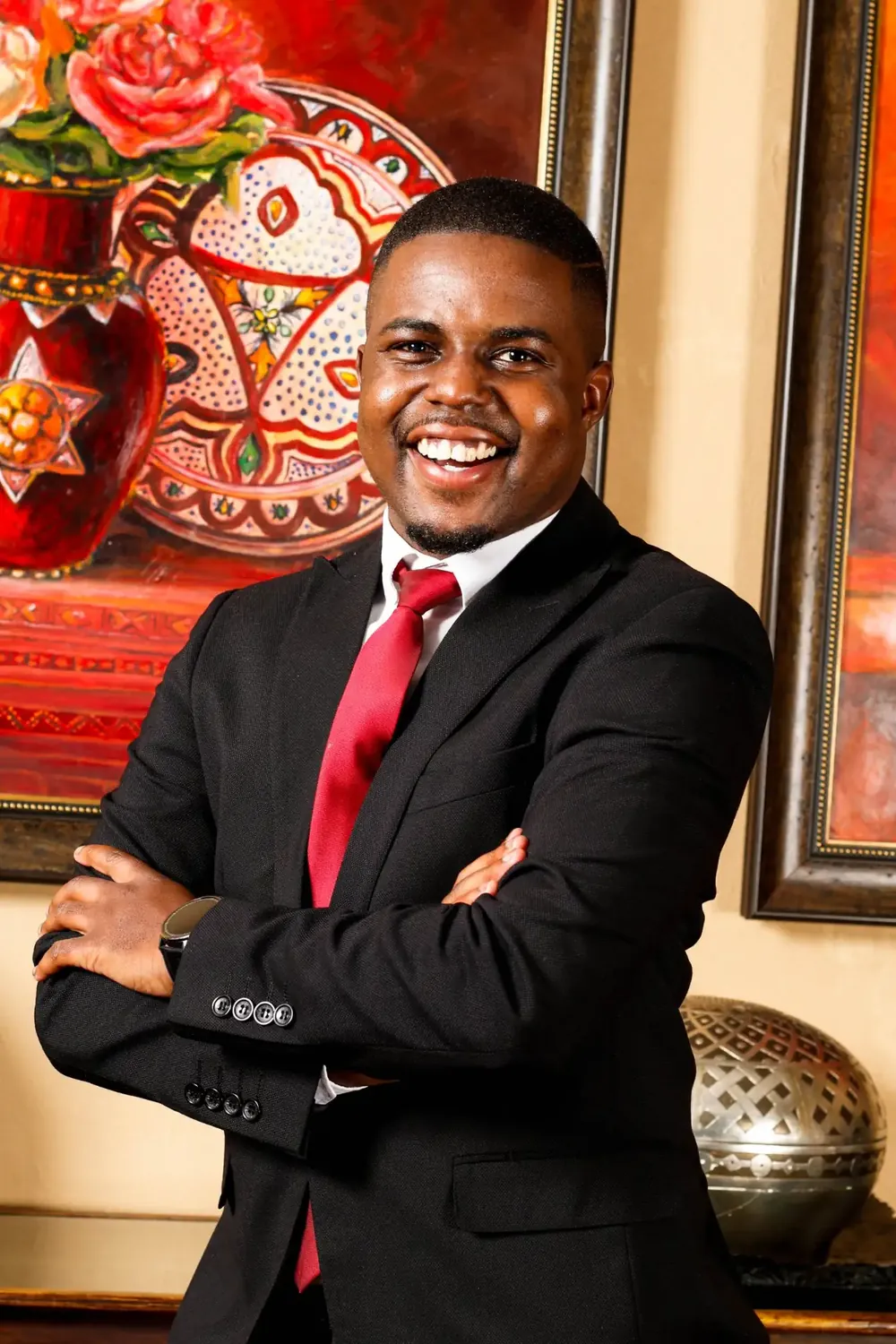 Andrew Tsuro in a black suit and red tie, arms folded