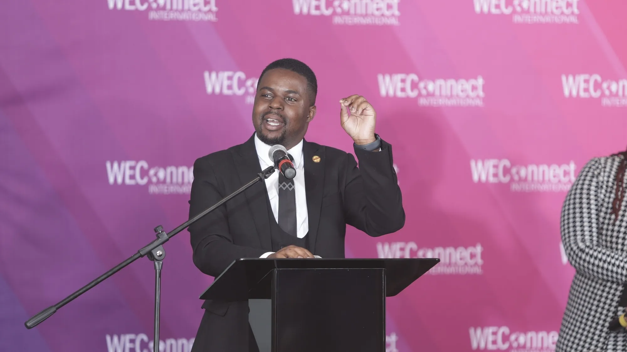 Andrew at a lectern in front of a WEConnect International backdrop