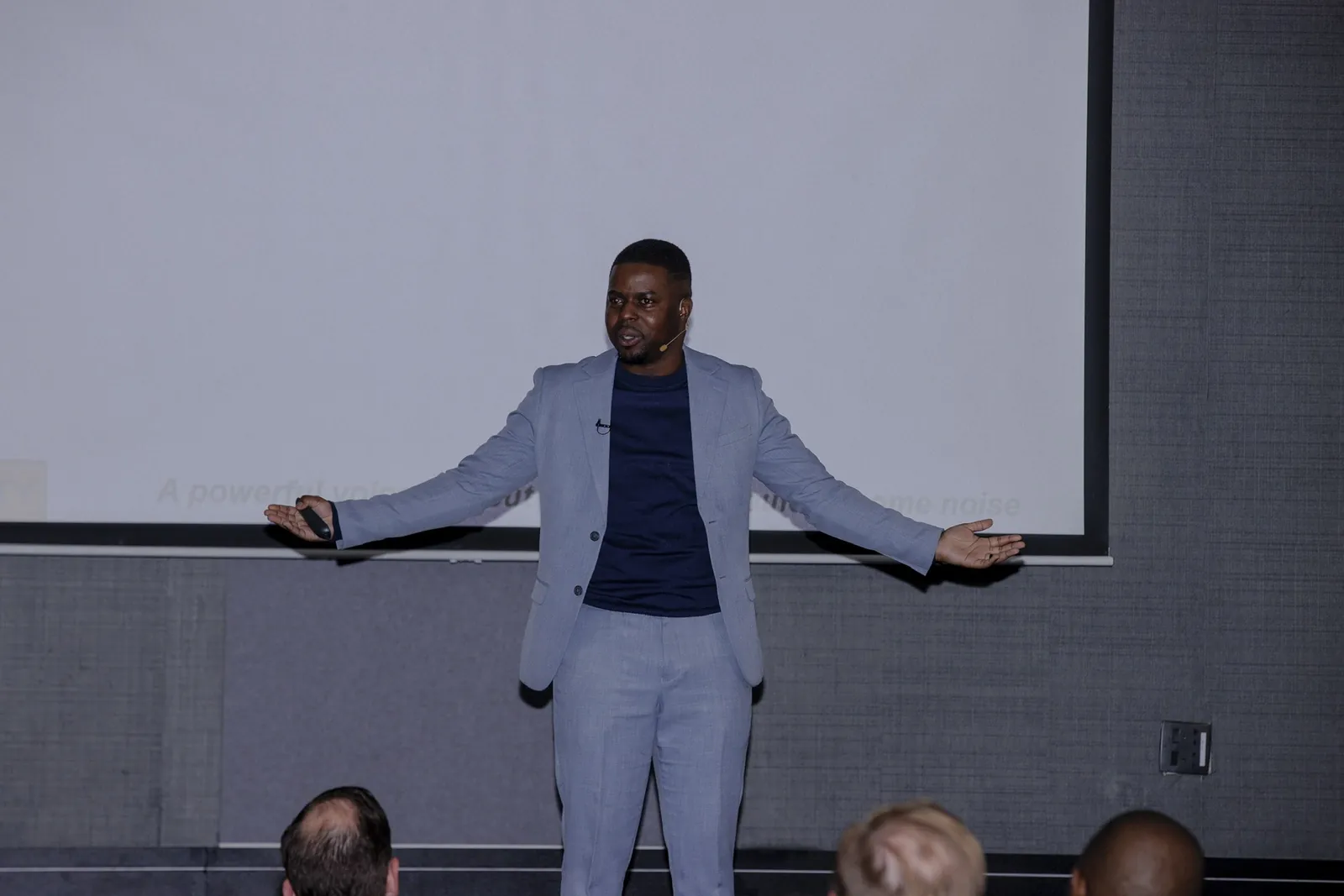 Andrew with both arms open in front of a seated group