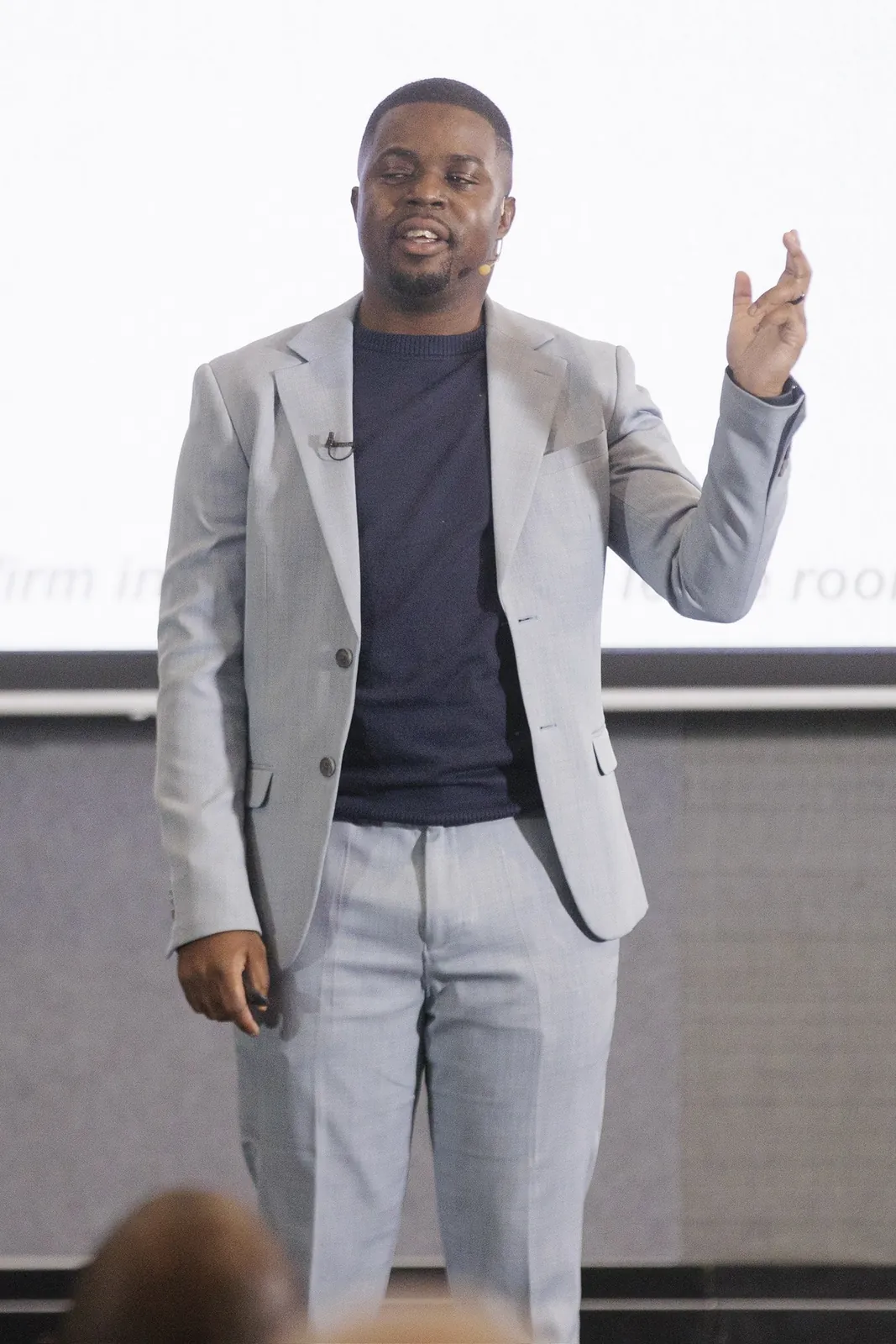 Andrew in a grey blazer making a point with one hand raised