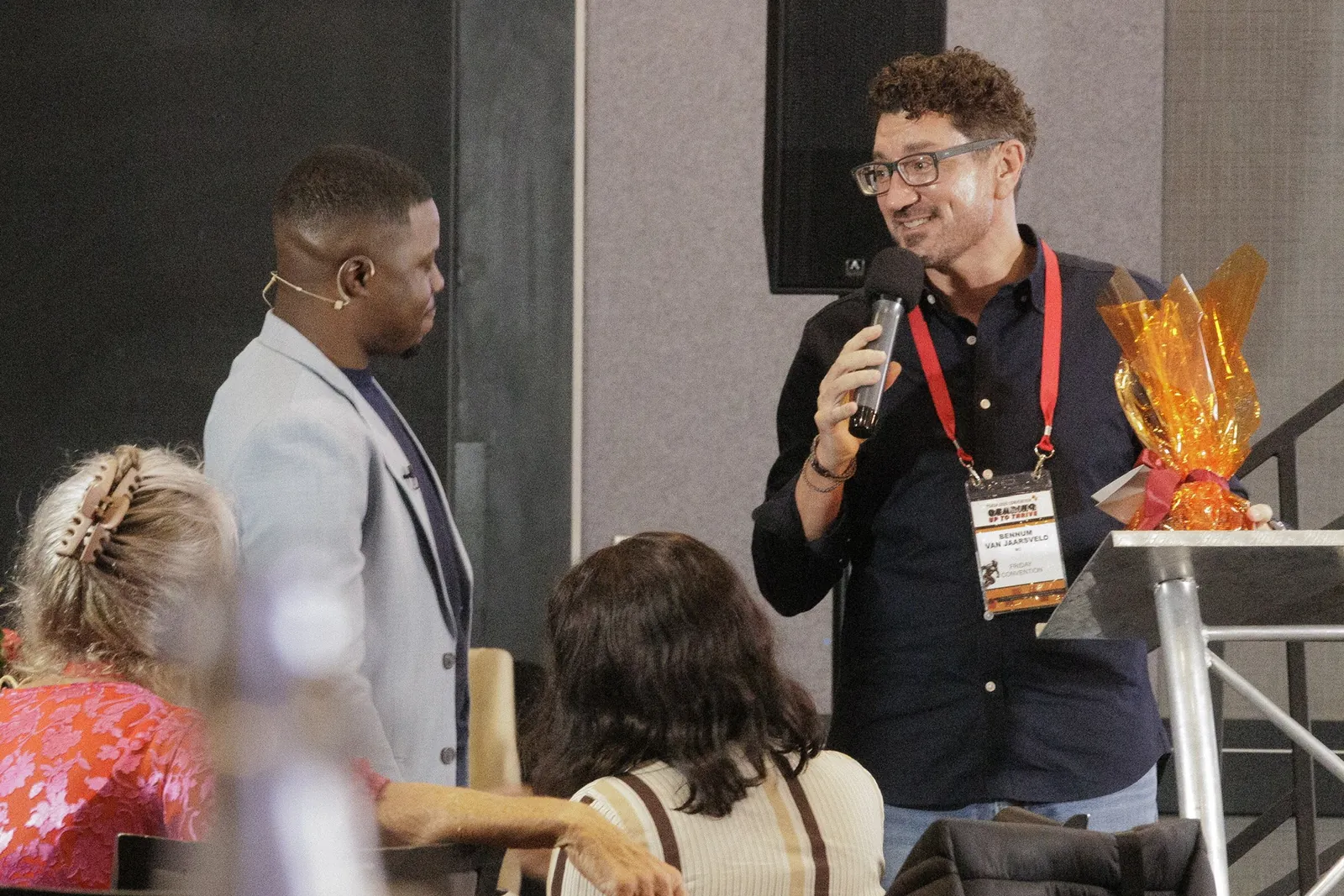 A participant speaking into a microphone while Andrew listens