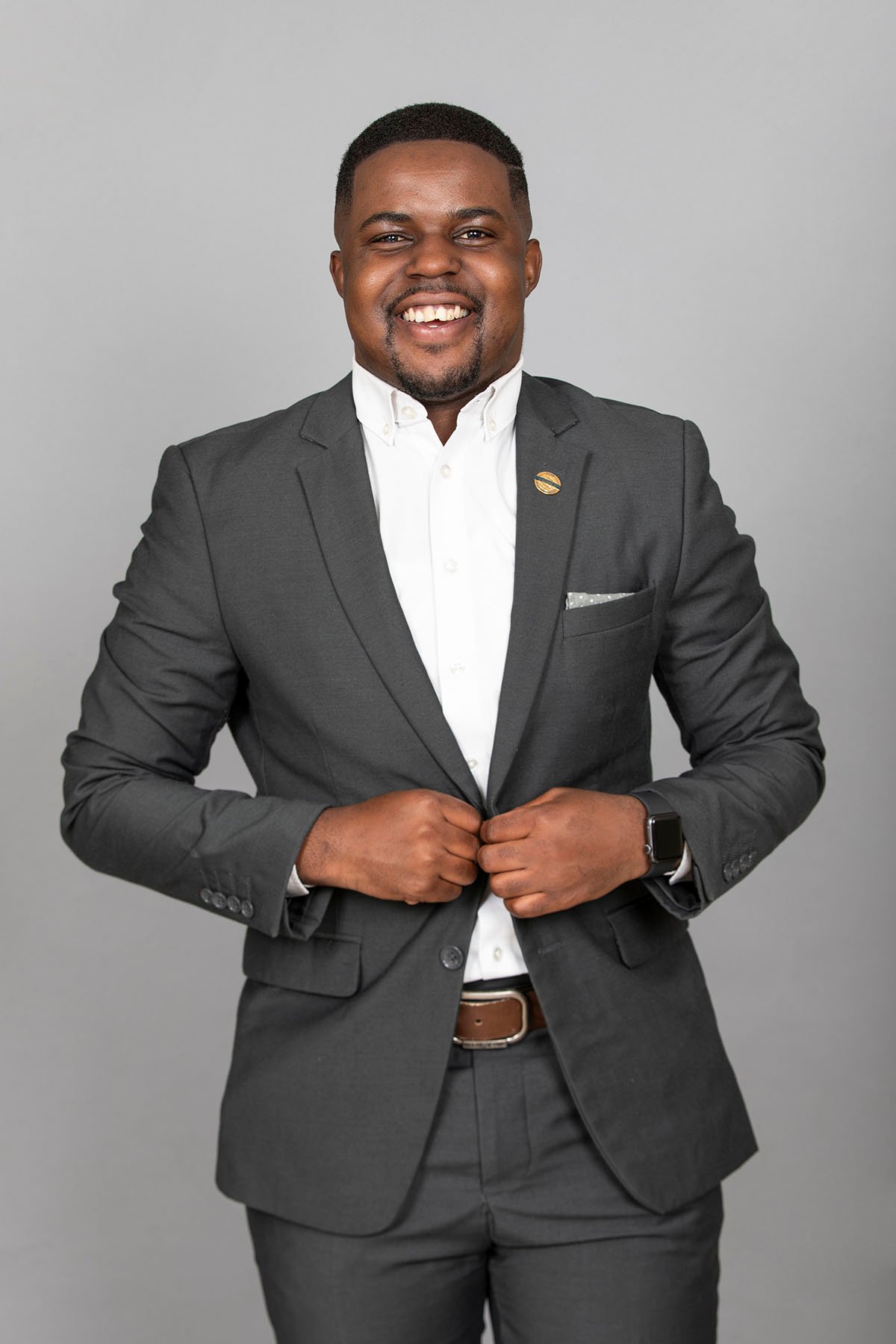 Andrew Tsuro smiling in a dark suit and open-collar white shirt.